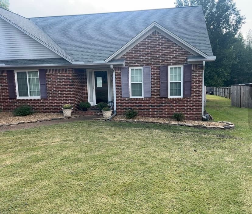 Brick home exterior with well-maintained lawn and landscaped garden.