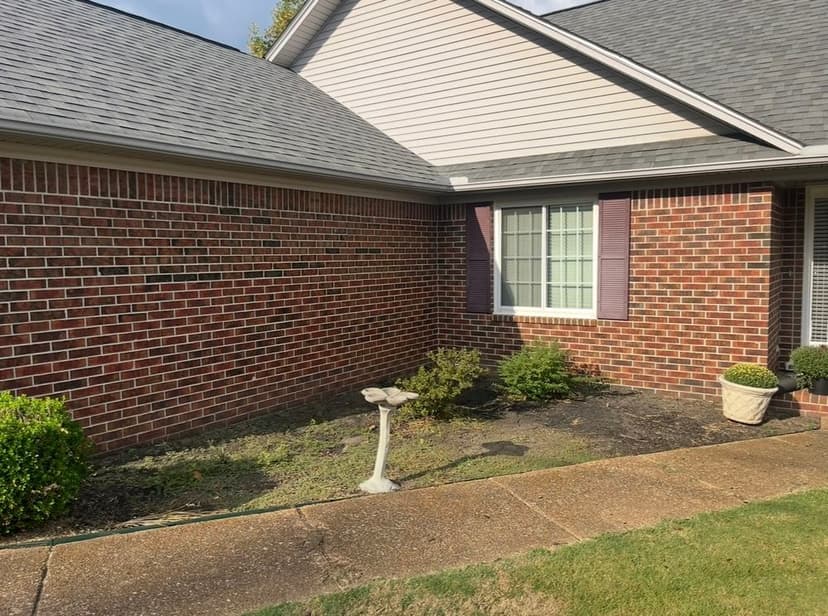 Brick home exterior with landscaped garden and decorative birdbath under clear sky.